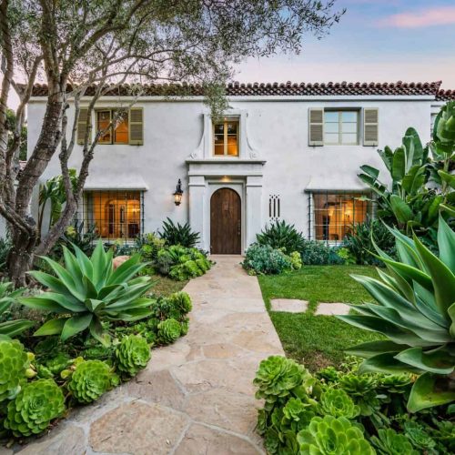 a home with a garden and landscaping on either side of it