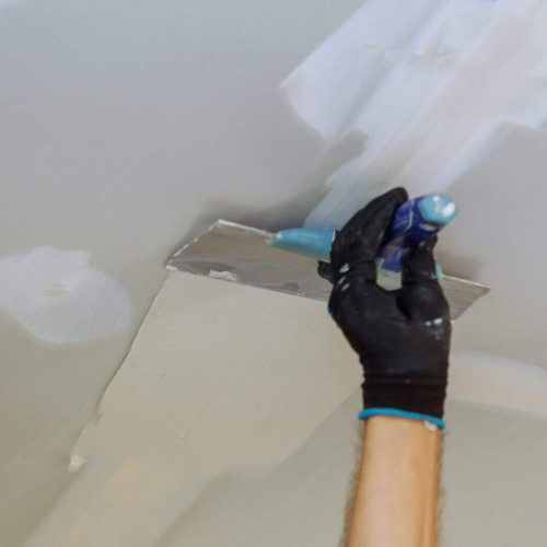 Closeup of a man aligning a wall with spatula and plastering gypsum cardboard wall