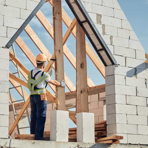 Concentrated man in safety gear building a house