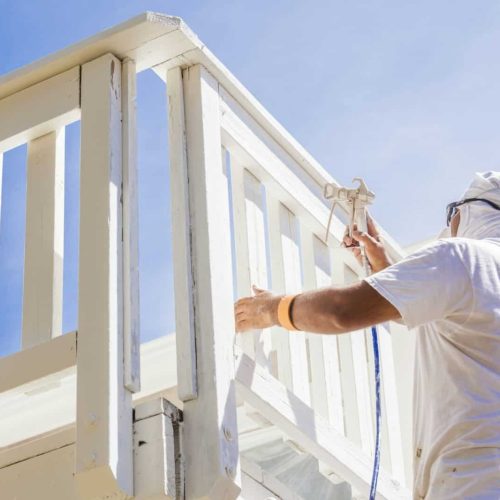 House Painter Spray Painting A Deck of A Home