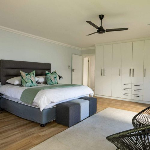 Interior of bedroom with bed and wardrobe by chairs at home