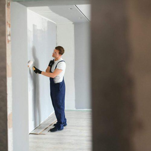 Worker painter paints a wall. Professional builder makes repairs.